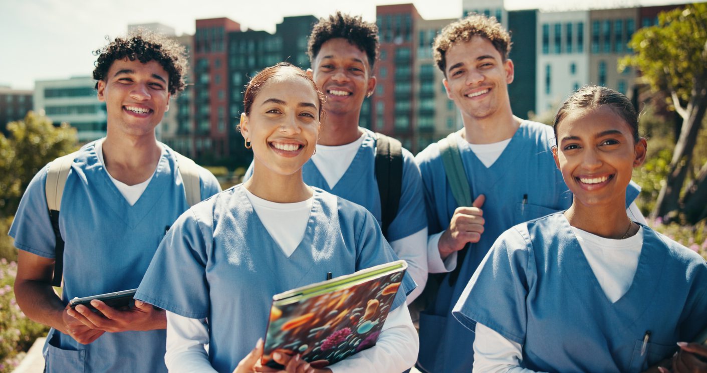 Group of nursing students in scrubs standing together outside on campus