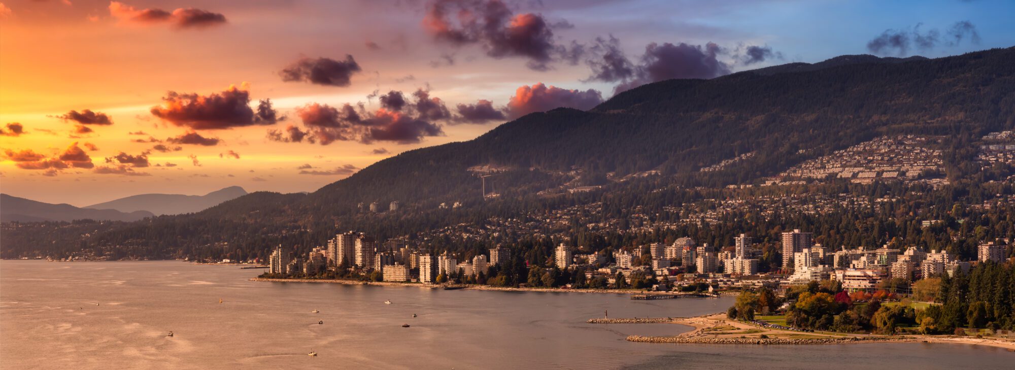 West Vancouver, British Columbia, Canada. Aerial Panoramic View of a modern cityscape on the Pacific Ocean Coast during an Autumn sunny and cloudy sunset.
