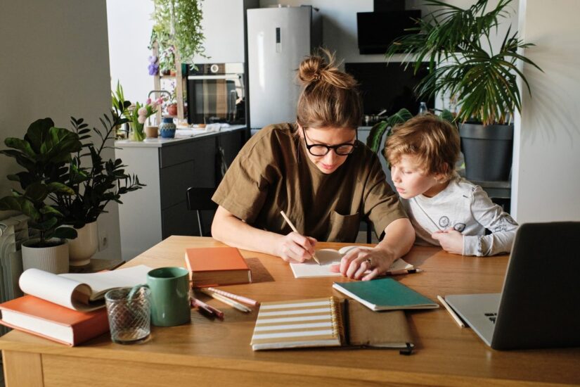 Child struggling with math homework at the kitchen table with a parent