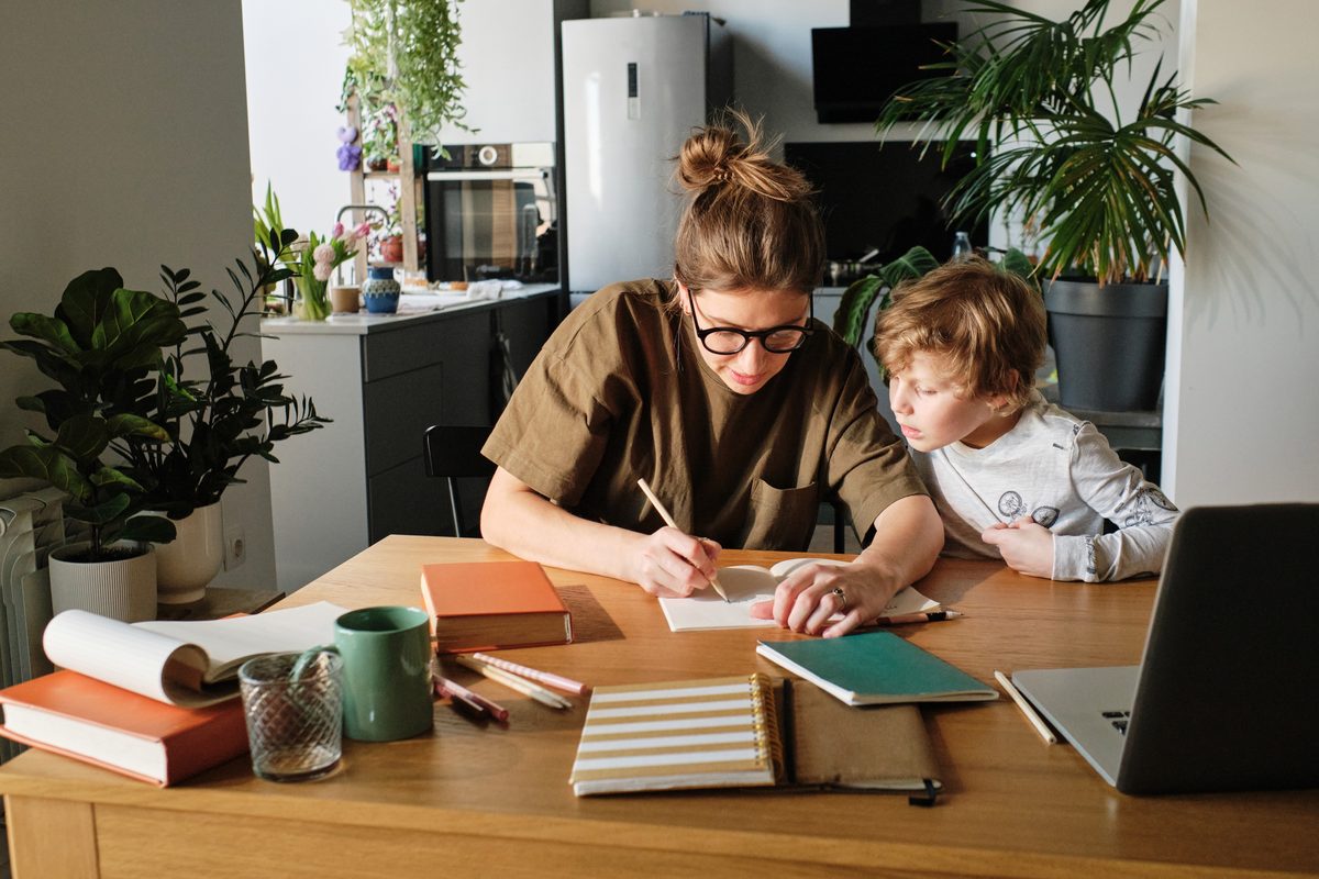 Child struggling with math homework at the kitchen table with a parent