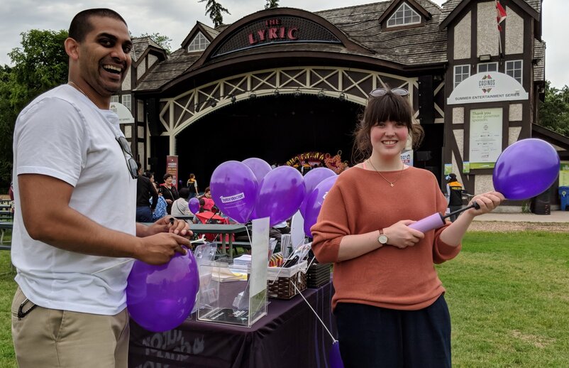 Woman and man blowing up purple balloons