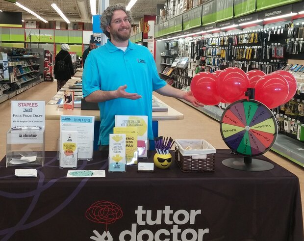 Man standing at a Tutor Doctor event table inside of a Staples store