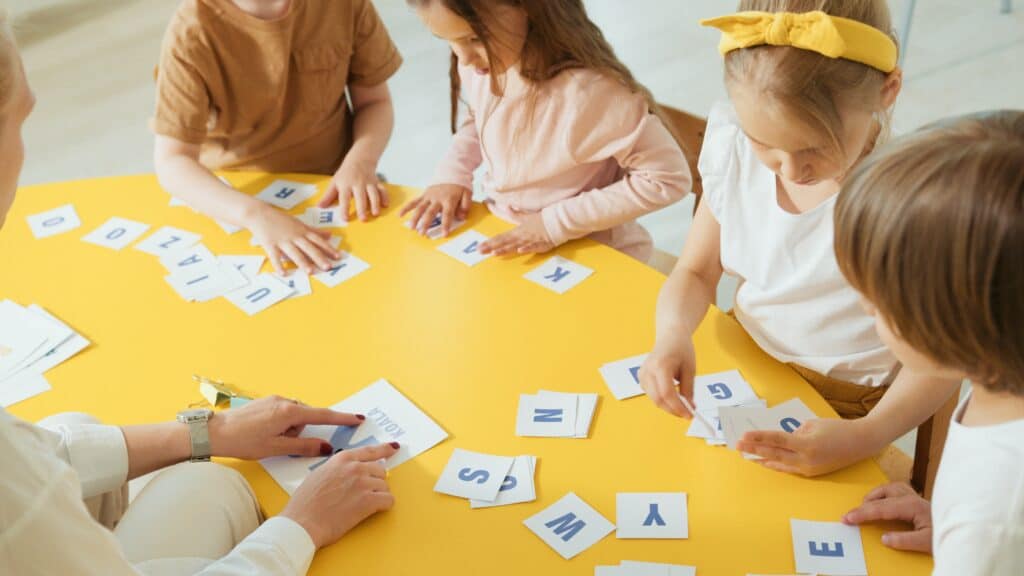 Children sitting around a table with letters on paper
