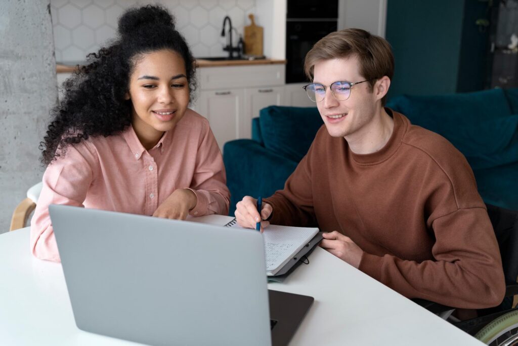 Two students sit at computer and work on a study schedule